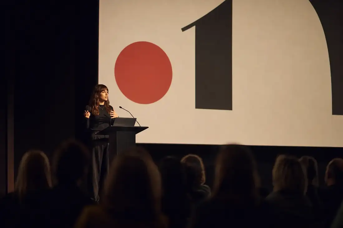 Maya Voss presenting on stage at a design conference